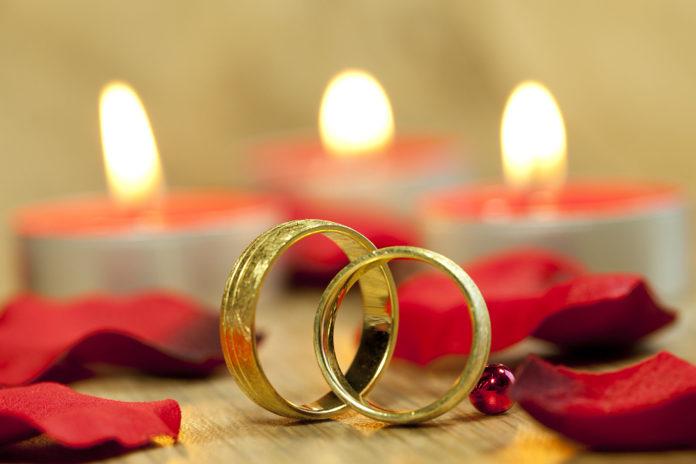 closeup-shot-wedding-rings-with-background-beautiful-red-roses-candles-table